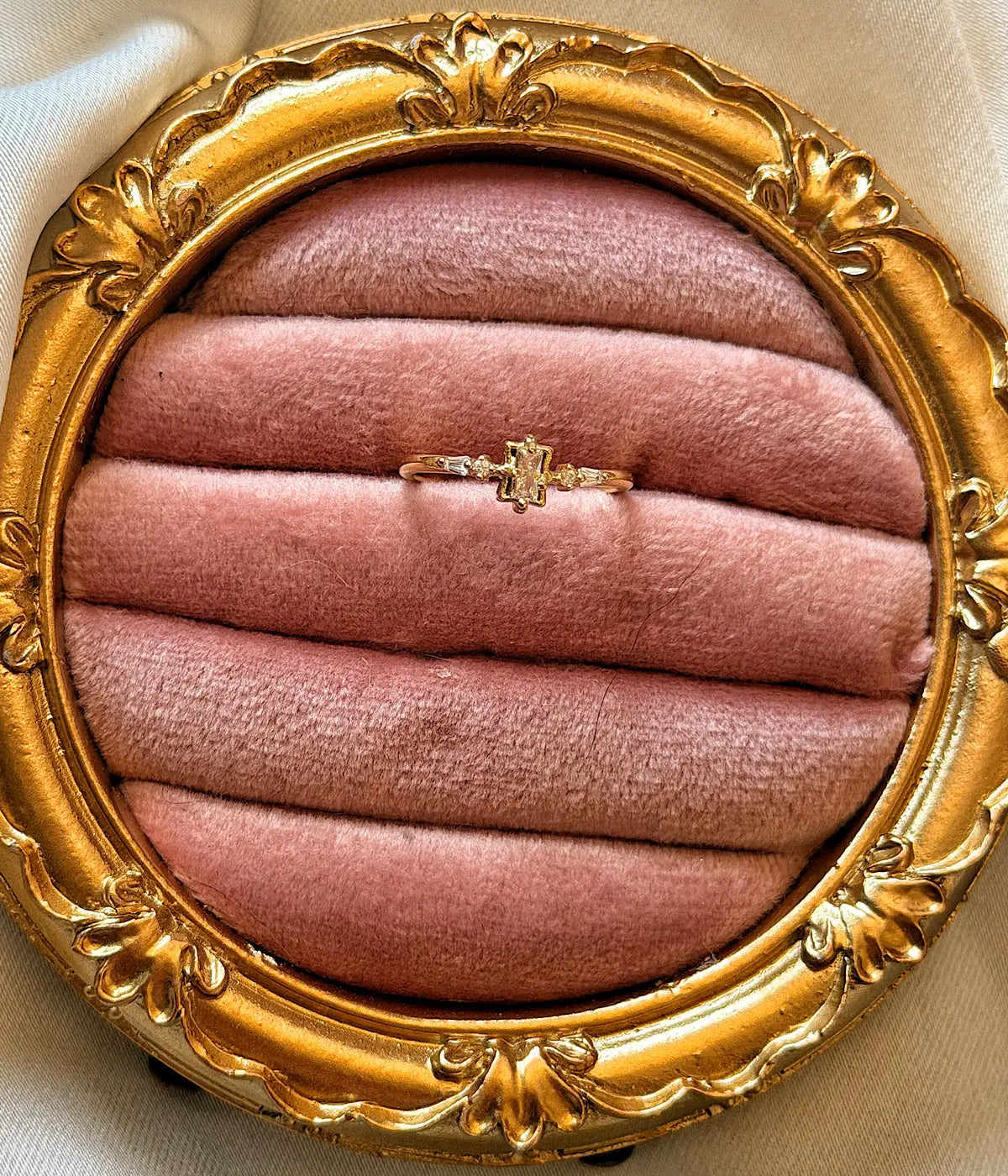 Baget ve yan taş detaylı gold kadın yüzük pembe kadife üzerinde