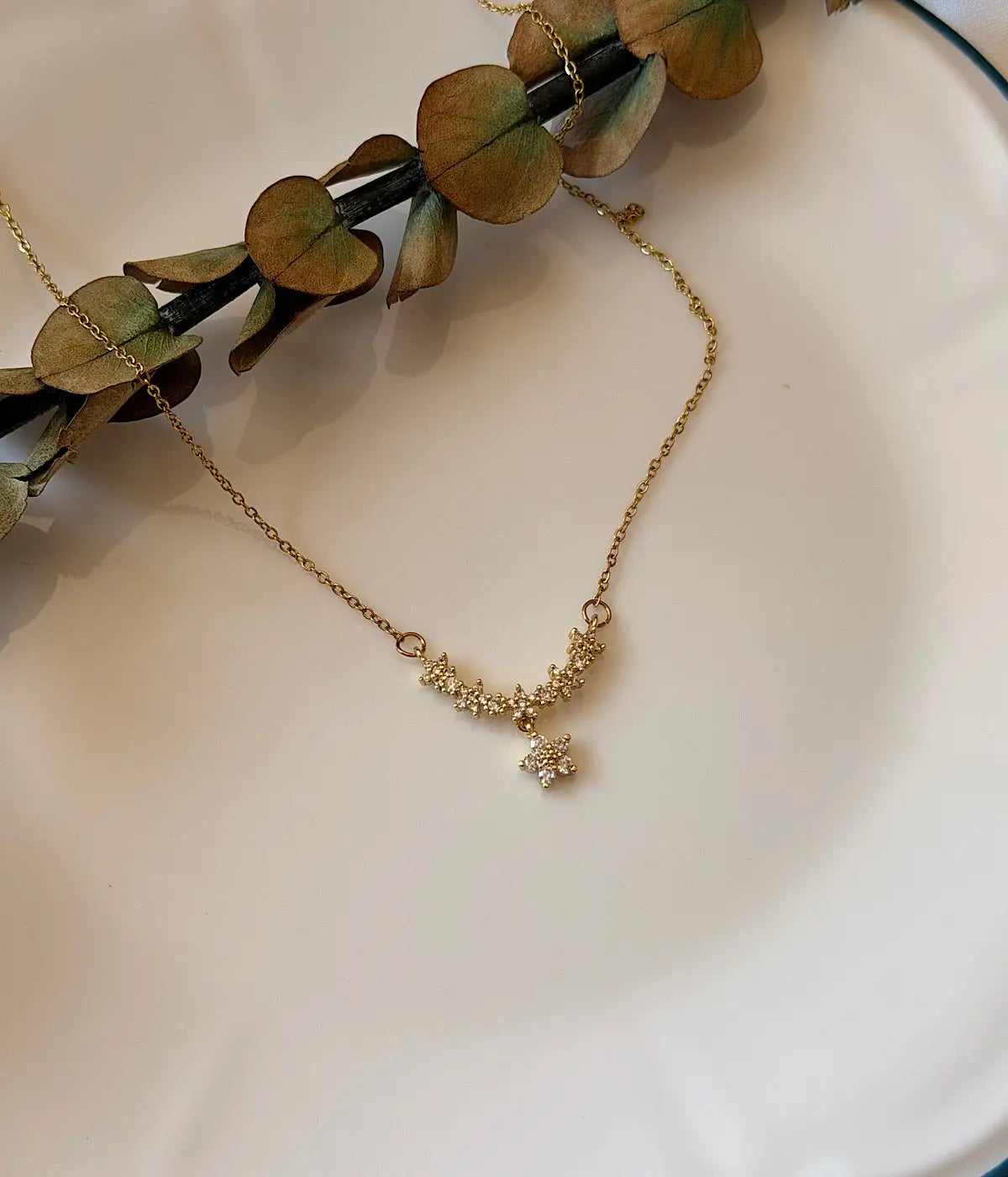 Çiçek motifli taşlı gold kadın kolye dekoratif tabak üzerinde ürün görünümü