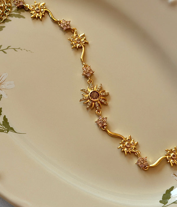 Gold çelik bilekliğin mor opal taşlı güneş motifi ve zincir detayları