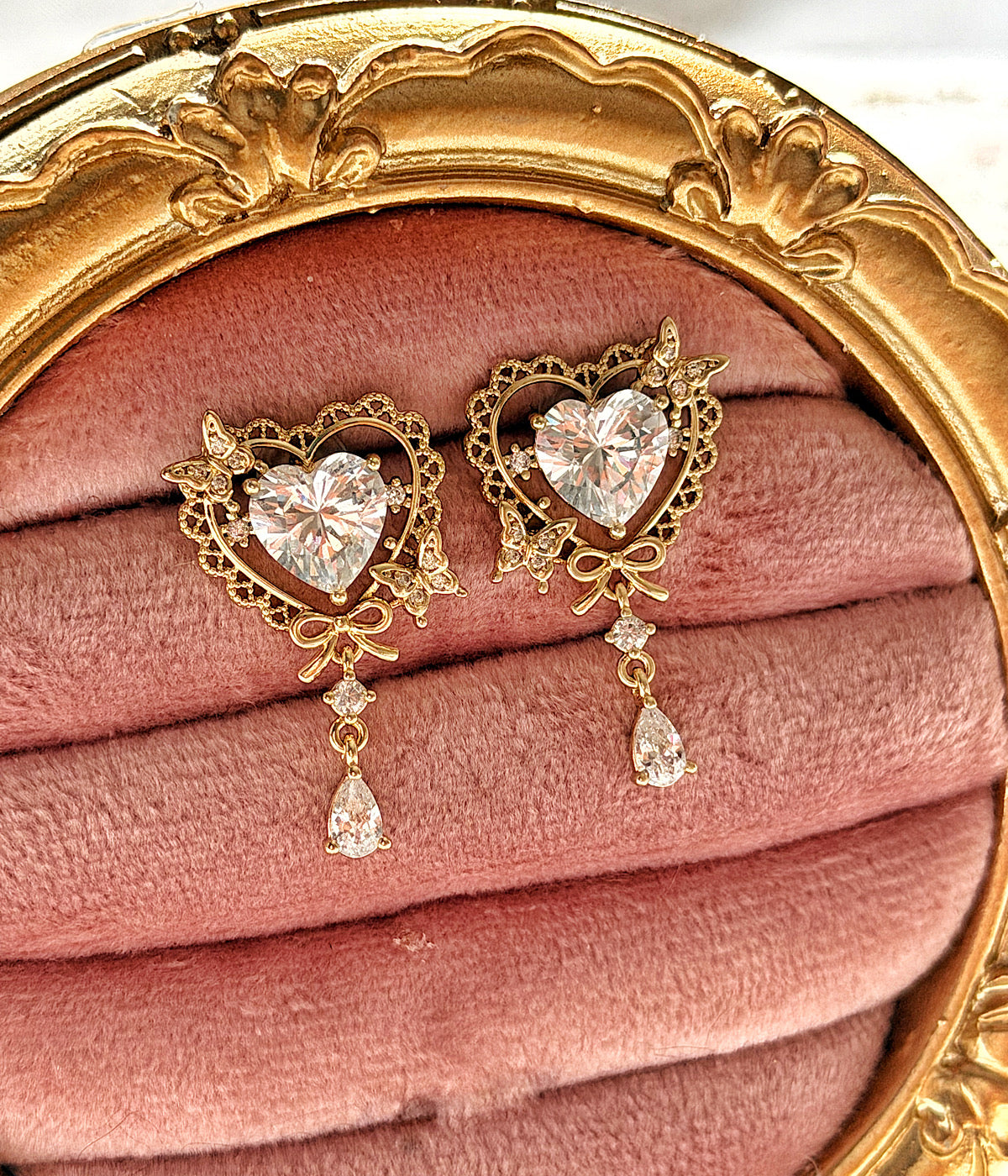 Pembe kadife üzerinde zirkon taşlı kalp ve kelebek detaylı sallantılı gold küpe