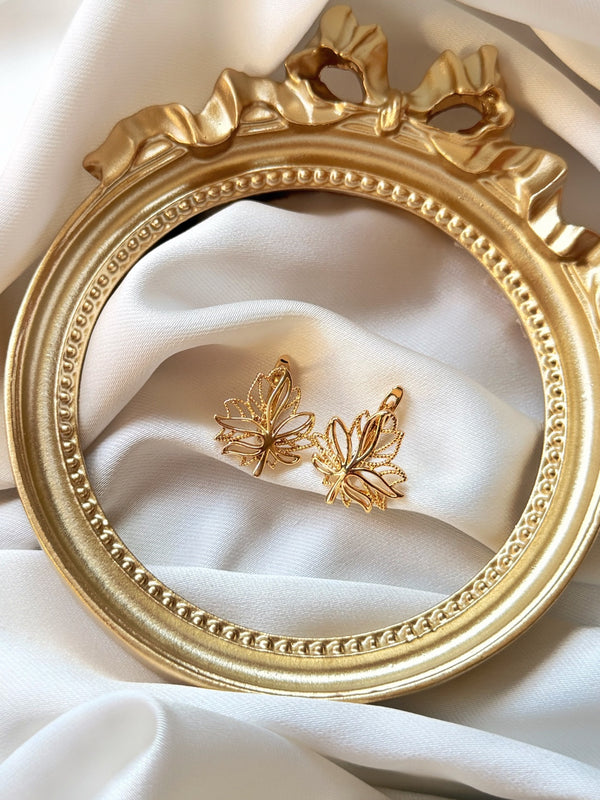 Yaprak figürlü gold kadın küpe çiftinin dekoratif çerçeve içinde görünümü