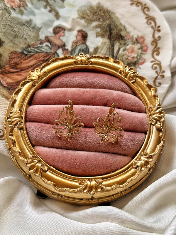 Ajur yaprak motifli gold küpe çiftinin pembe kadife üzerinde görünümü