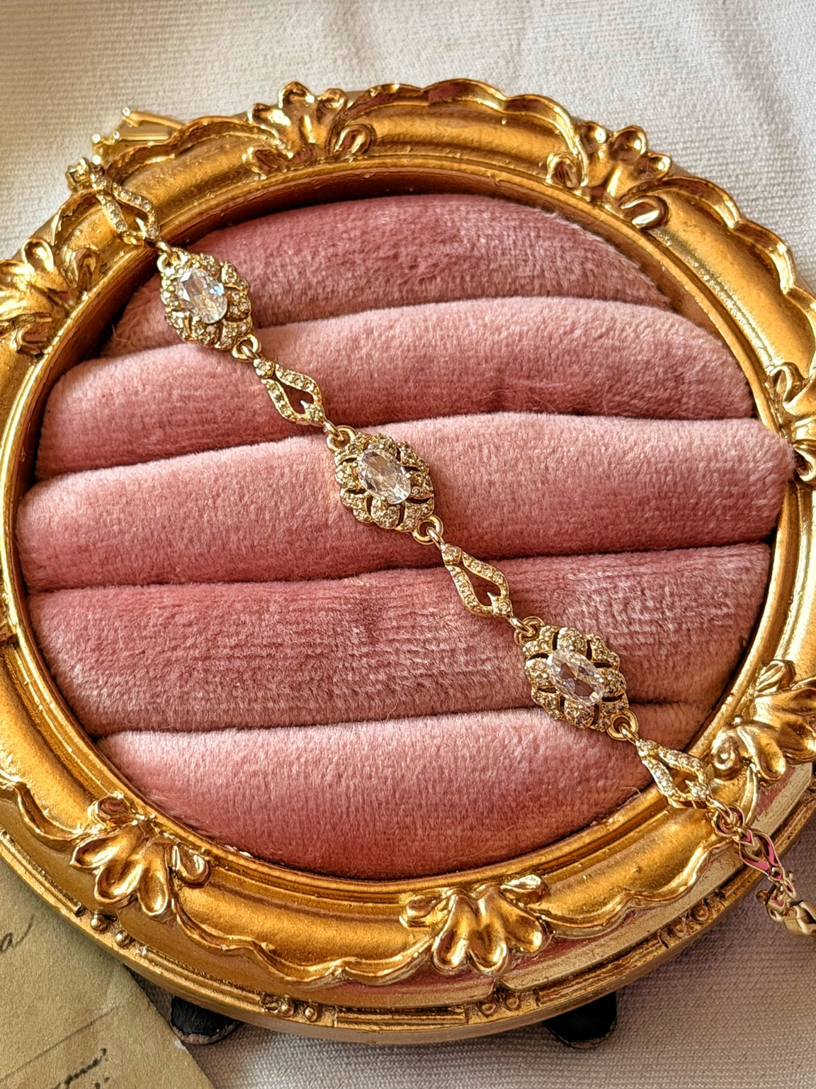 Pembe kadife üzerinde gold bilekliğin oval taşlı çiçek motifleri ve damla biçimli bağlantıları
