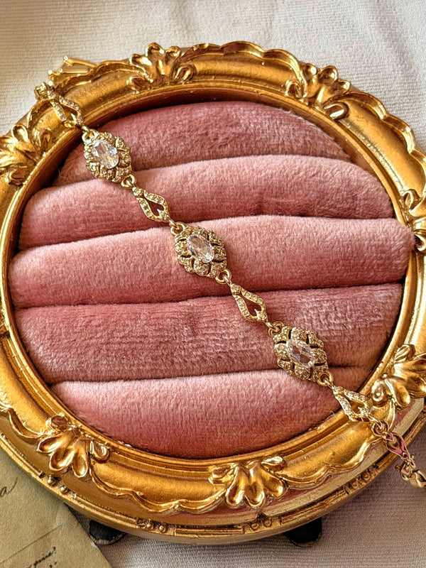 Pembe kadife üzerinde gold bilekliğin oval taşlı çiçek motifleri ve damla biçimli bağlantıları