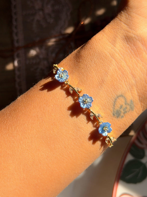 Mavi takı setindeki üç mavi sedef çiçekli gold bilekliğin bilekte görünümü
