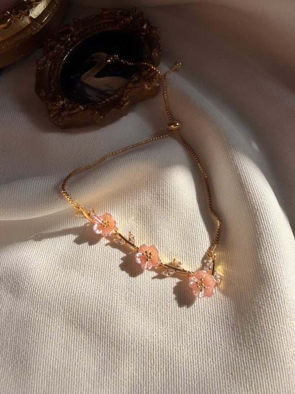 Pembe sedef çiçekli asansörlü gold bileklik saten kumaş üzerinde