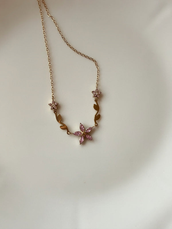 Pembe çiçekli ayarlanabilir gold çelik kolyenin düz zeminde görünümü
