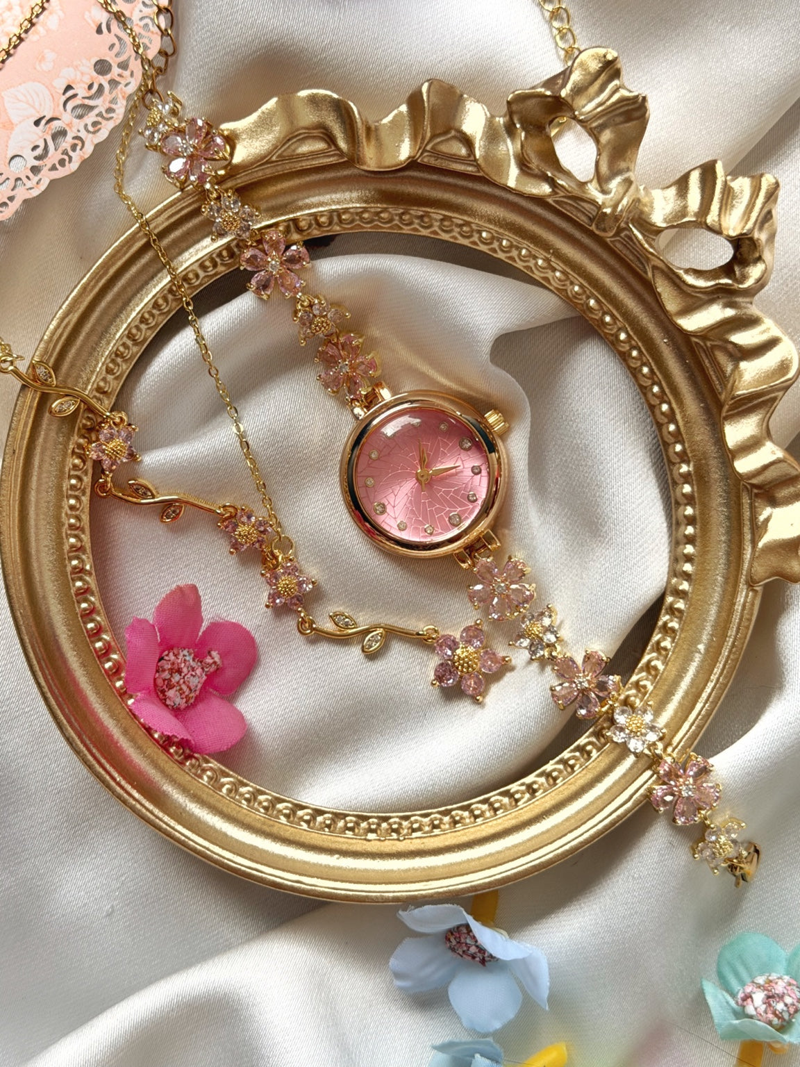 Pembe çiçekli gold kadın saat ve Y kolye 2'li takı setinin saten ve gold çerçeve üzerinde birlikte görünümü