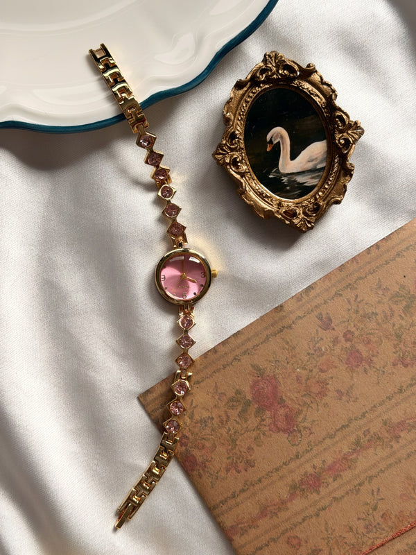 Pembe taşlı gold bileklik saat vintage kuğu çerçevesi yanında tam uzunlukta sergileniyor