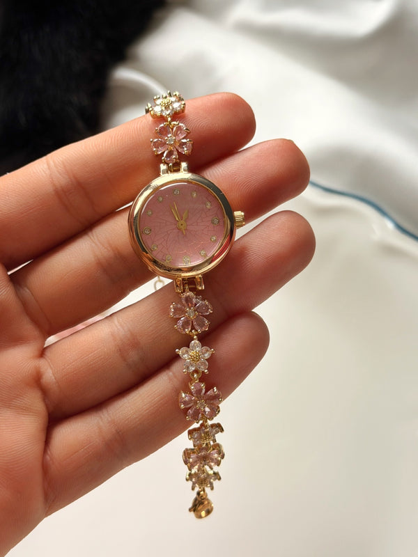 Pembe kadranlı çiçek detaylı gold kadın bileklik saatin elde yakın görünümü