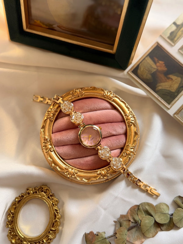 Pembe kadranlı beyaz gül detaylı gold metal kadın saat yakın plan görünümü