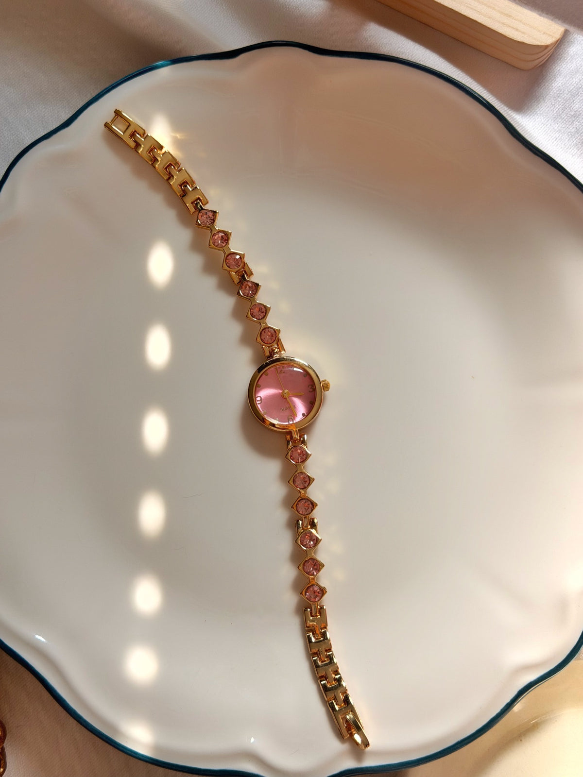Pembe taşlı yuvarlak kadranlı gold kadın saat, metal bileklik kordonunun tamamı beyaz tabakta