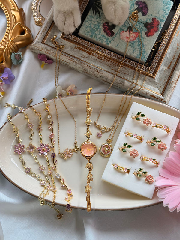 Pembe kelebek saat, üç kolye, dört bileklik ve iki farklı yüzük modelinden oluşan gold tonlu 10 parçalı kadın takı seti