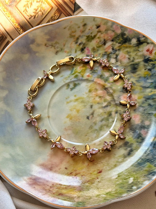 Pembe taşlı çiçek dalı gold kadın bilekliğin çiçekli porselen üzerinde görünümü