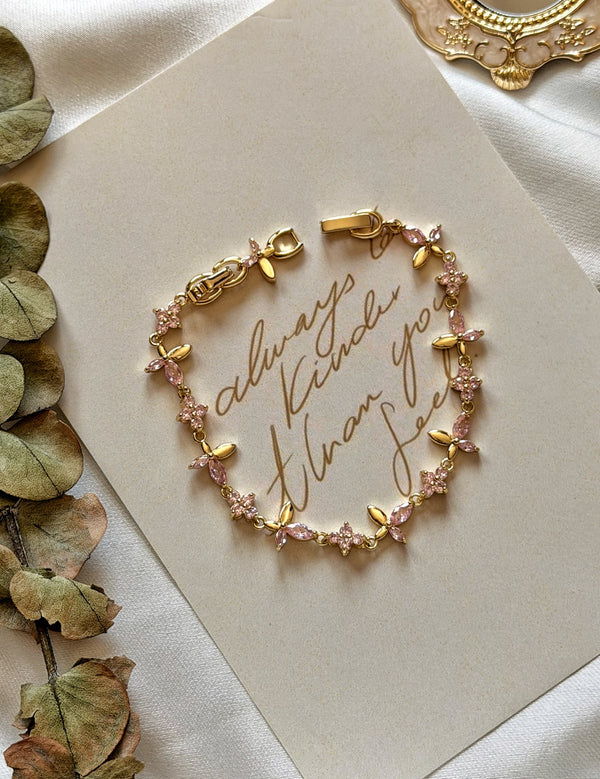 Pembe taşlı çiçekli gold kadın bilekliğin dekoratif sunum üzerindeki görünümü