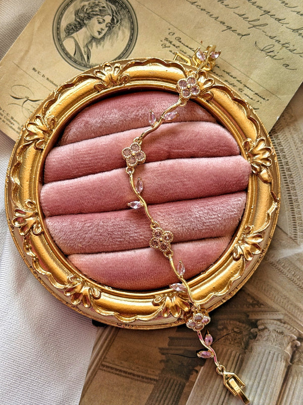 Pembe taşlı gold çiçek bilekliğin pembe kadife ve gold çerçeve üzerindeki görünümü