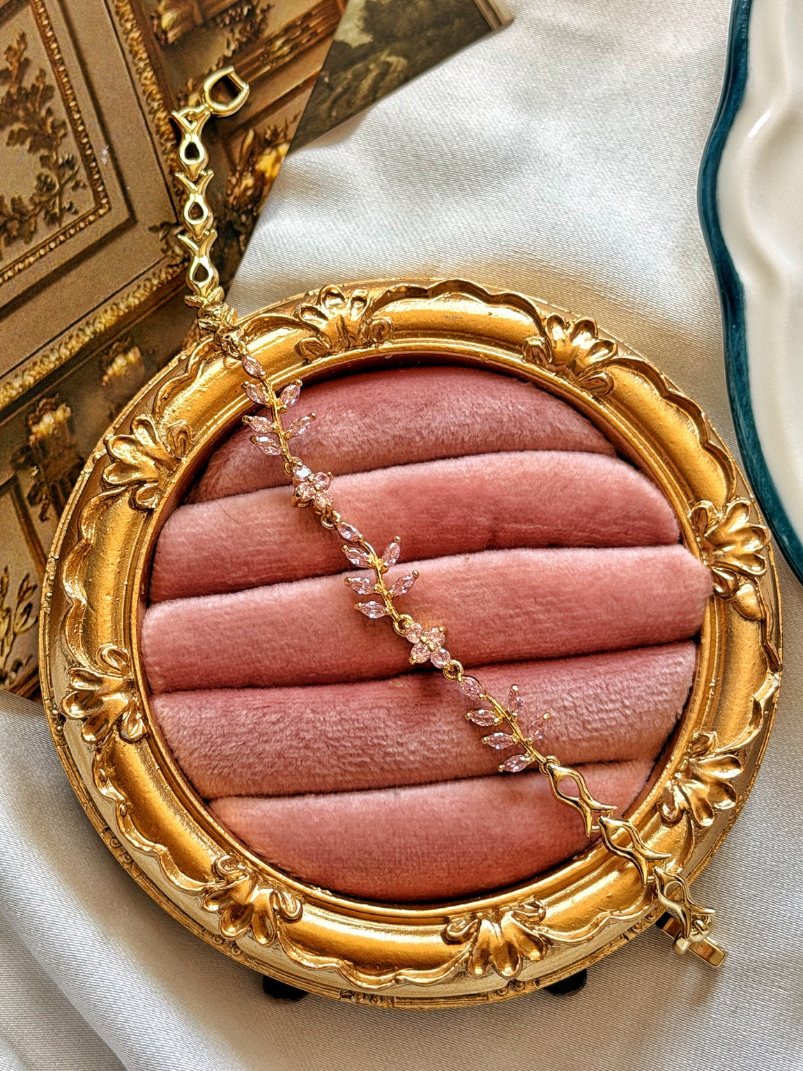 Pembe taşlı sarmaşık dal gold kadın bilekliğin dekoratif kadife sunumda tam görünümü