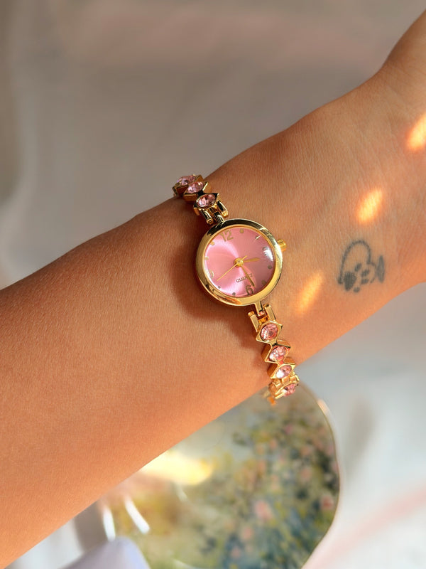Pembe kadranlı ve pembe taşlı gold kadın bileklik saat bilekte kullanım, yuvarlak kadran ve metal kordon