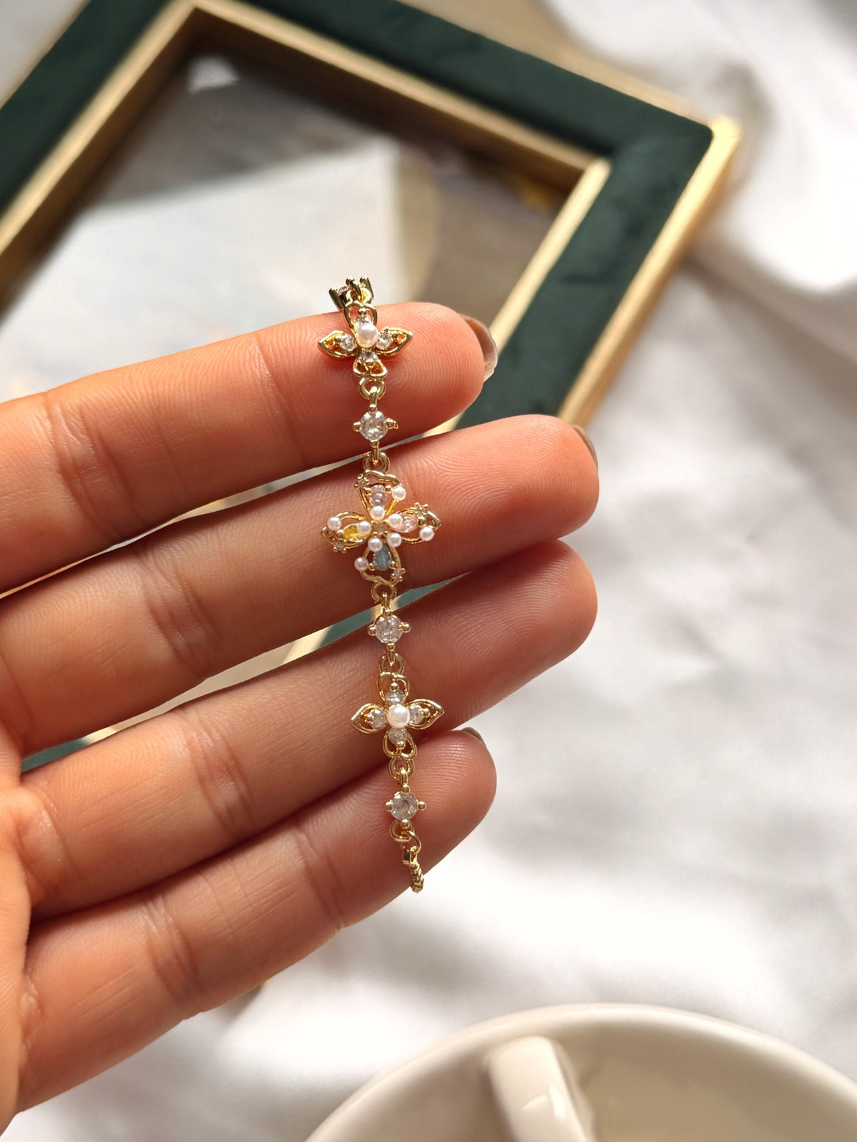 Renkli taşlı çiçek ve inci görünümlü detaylarıyla ayarlanabilir gold bileklik yakın çekim