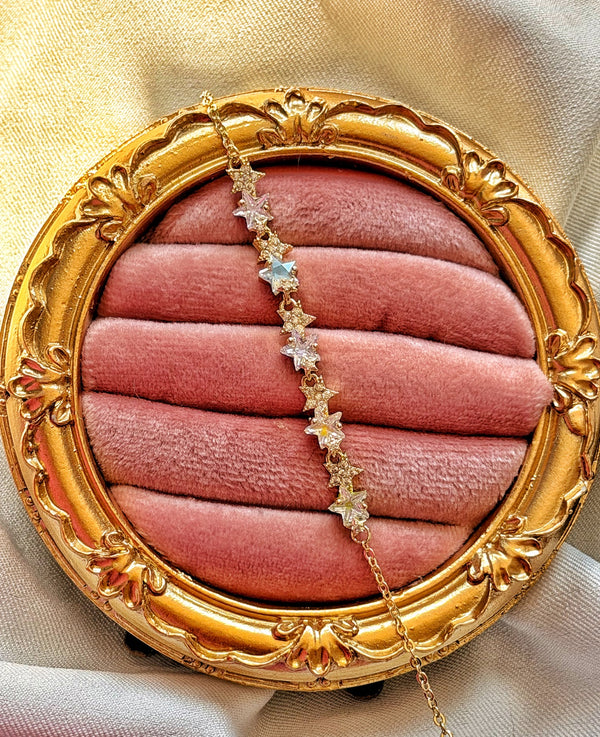 Gold çerçeveli pembe kadife üzerinde sıralı renkli ve küçük taşlı yıldız motifli bileklik.