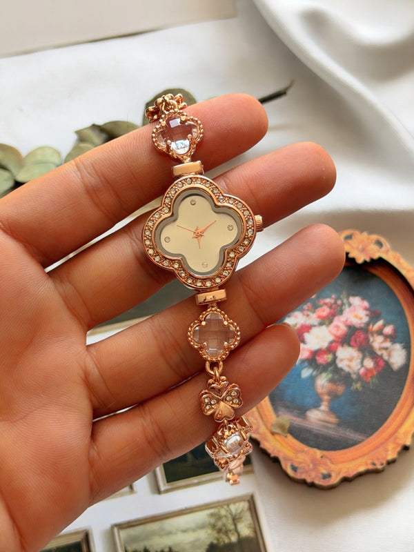 Rose gold kadın saatin yonca kadranı, şeffaf yonca taşları ve kelebek detaylı kordonunun elde görünümü