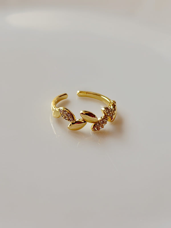 Taşlı yaprak motifli gold kadın yüzüğün açık renk zeminde, açık uçlu halkasıyla tam görünümü