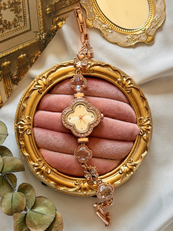 Taş çevrili yonca kadranlı rose gold kadın saatin pembe kadife sunum üzerinde görünümü