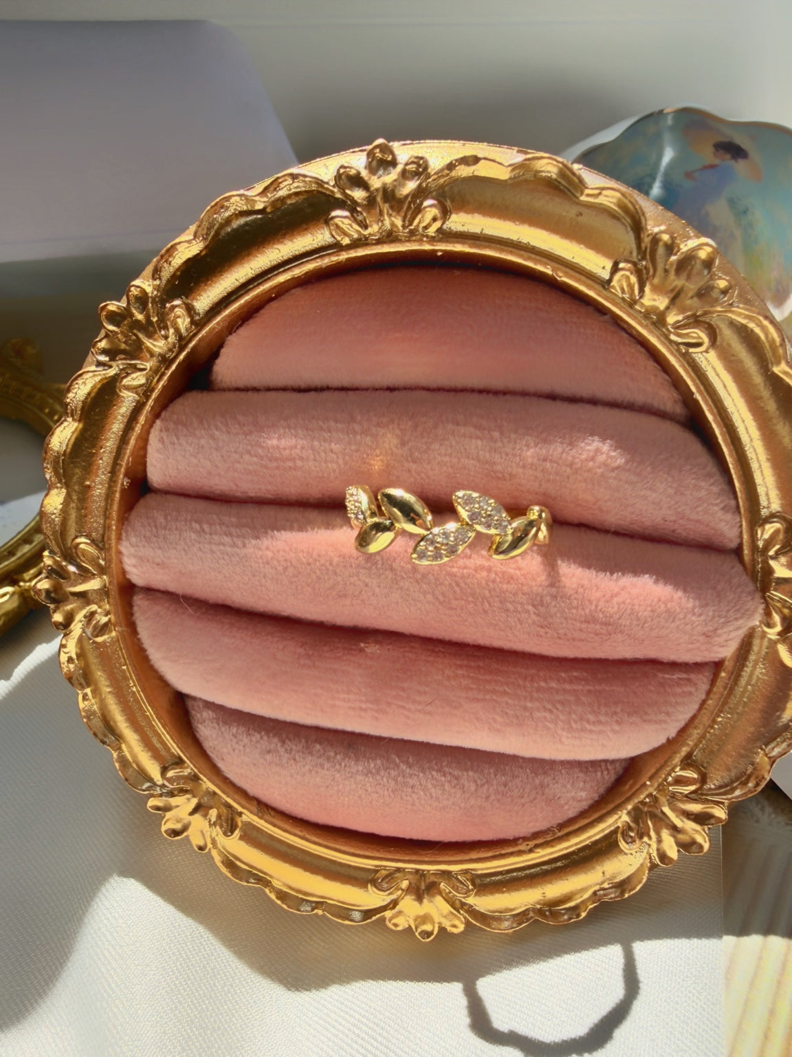 Yaprak motifli gold yüzüğün pembe kadife ve işlemeli gold çerçeve üzerindeki stil çekimi