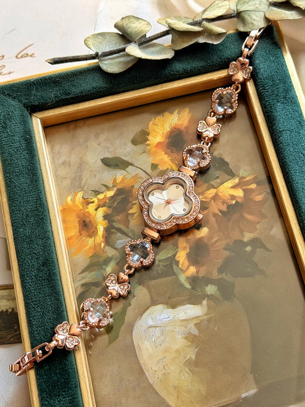 Şeffaf yonca taşlı rose gold bileklik saatin çiçekli tablo üzerinde dikey tam görünümü